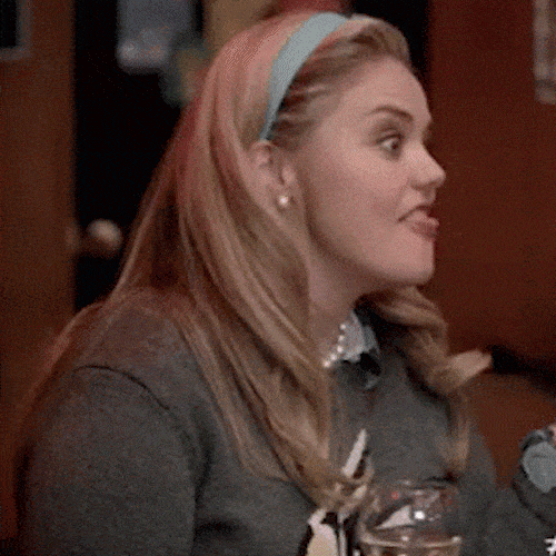 A young woman in a headband pulls out a paper coupon and waves it.