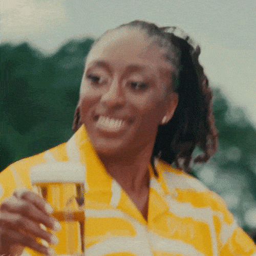 Woman in a yellow shirt smiling and holding a drink