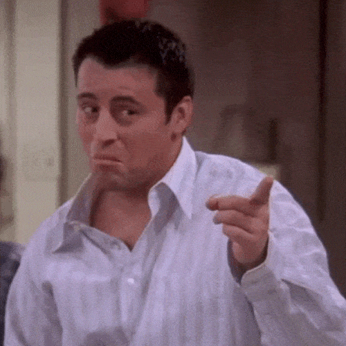 Man in a light blue shirt pointing finger guns