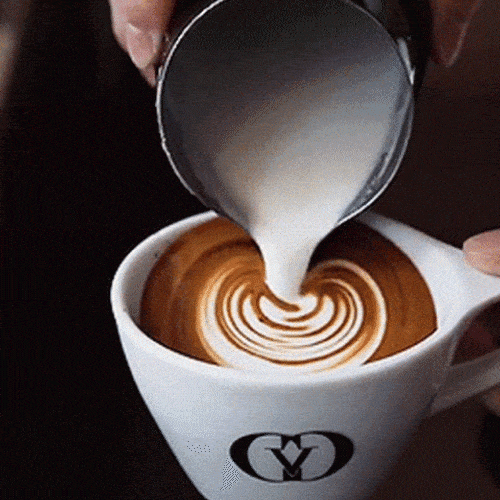 Milk is poured into a cup of coffee, creating a heart-shaped latte art pattern.