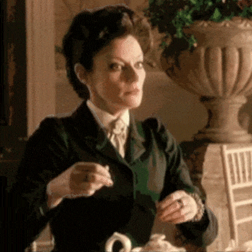 Person in formal clothing gently placing or preparing tea at a table