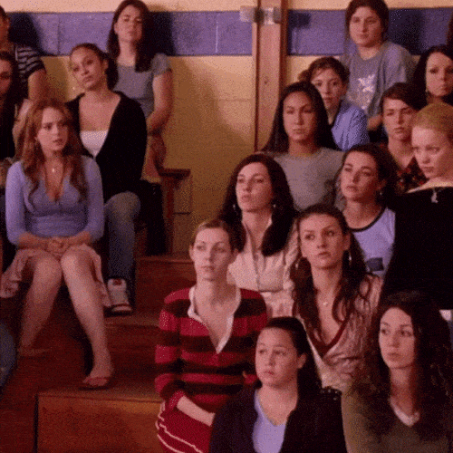 A room full of women in a school hall raise their hands.