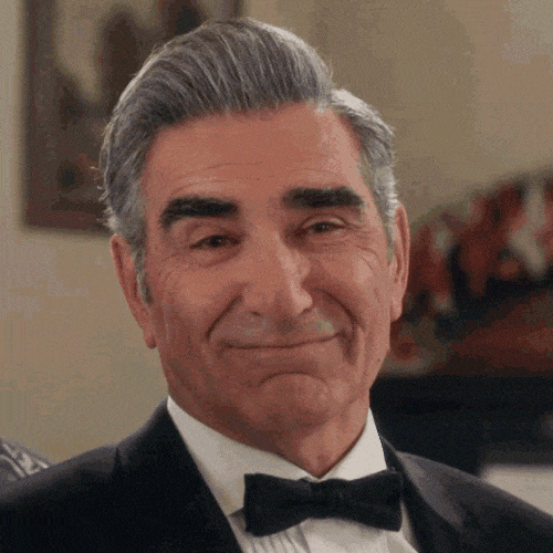 Older man in a tuxedo giving a calm, subtle smile