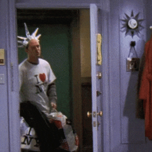 Man wearing novelty crown entering an apartment doorway