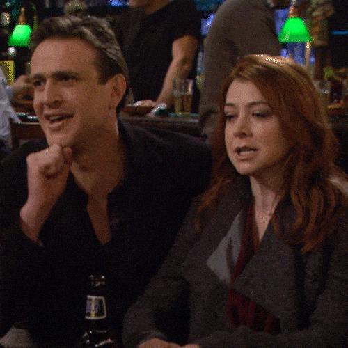 A man and a woman sitting together at a bar high-five each other.