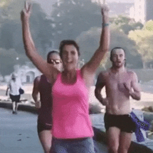 Runners cheer and raise their arms as they jog along a waterfront route.
