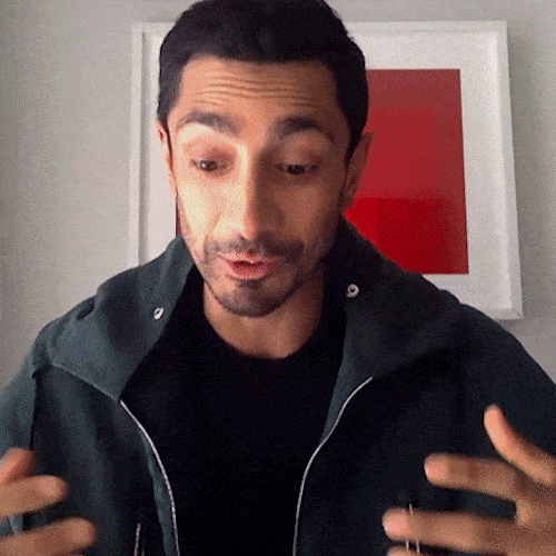 A man in a dark jacket gestures with his hands as he talks.