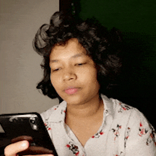 A woman looks at her phone and chuckles.