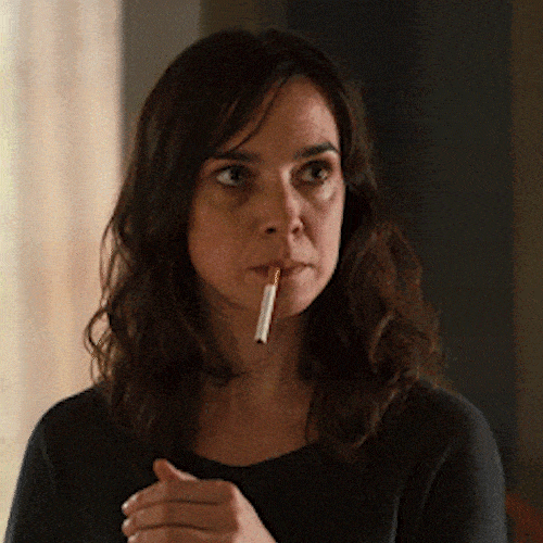 A woman takes a cigarette out of her mouth with a determined look.