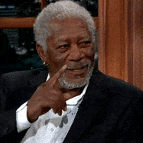 Older man in a suit pointing knowingly 