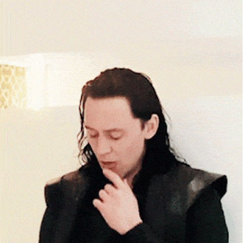 A man with long dark hair thoughtfully strokes his chin, then opens a book.