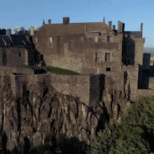 A historic stone castle sits on top of a rocky cliff.