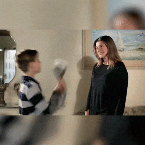 A boy in a striped shirt hands a woman a bundle of cash, and she happily takes it.