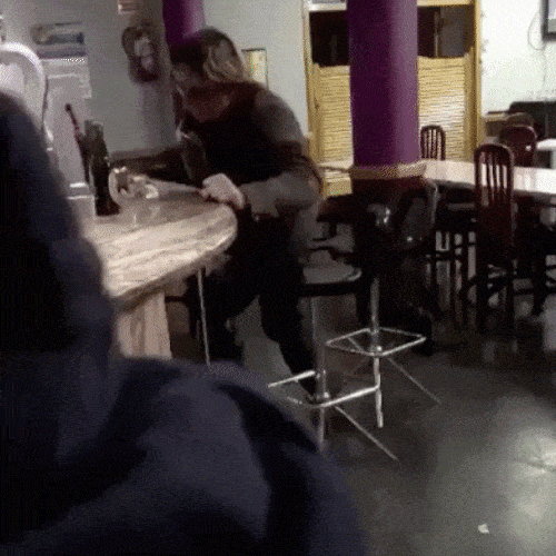 A person falls over his chair in a bar 