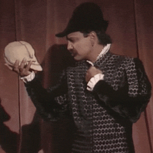 Man in historical costume holding a skull in a Shakespeare-style scene 