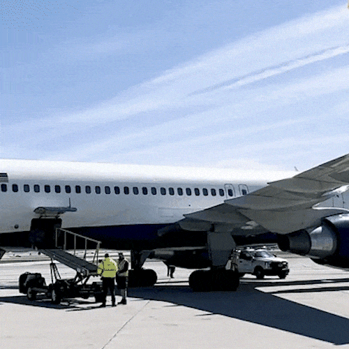 A traveler with a backpack runs across the tarmac toward a plane.