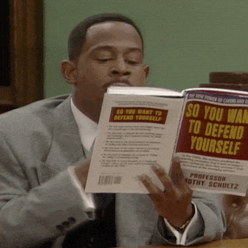 A man in a gray suit reads a law book at a desk.