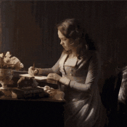 Person writing a letter at a desk in a historical setting