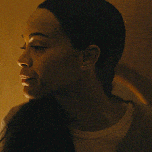 A woman in a dimly lit room takes a slow, deep breath.