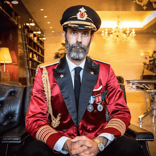 A man in a captain's uniform checks his wristwatch.