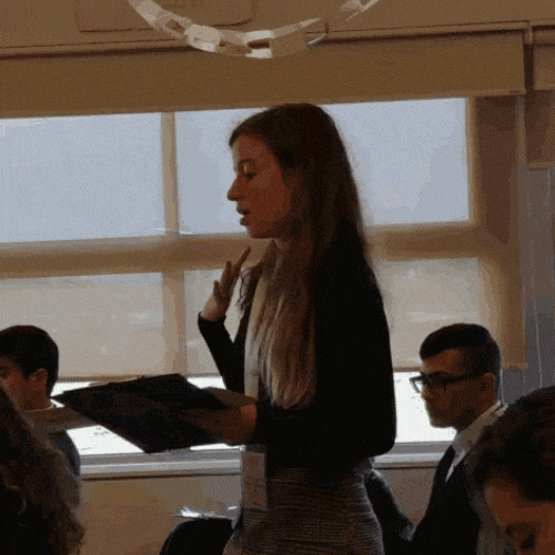 Trainer standing in a classroom presenting while holding a folder