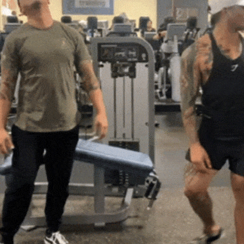 Two men at the gym high-fiving each other.