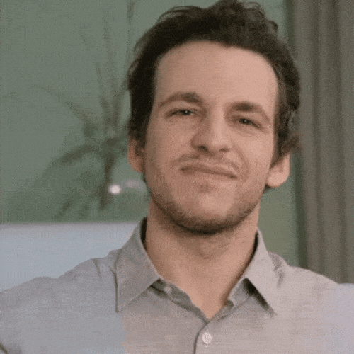 Man in a grey shirt giving a diplomatic half-smile