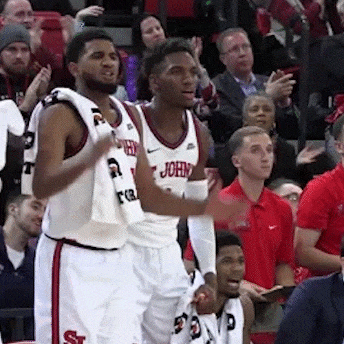 Basketball players celebrate on the sideline, and one throws a towel into the air.